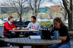 Two students working on their laptops at an outdoor table